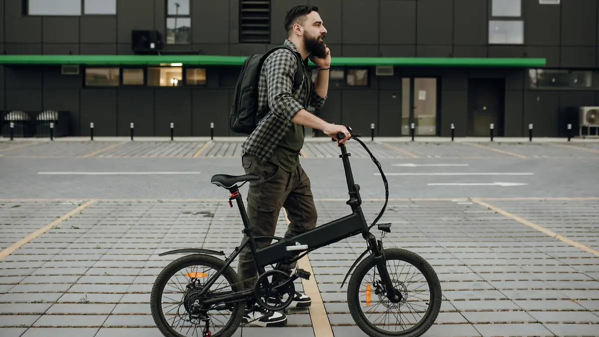 Commuter pushing his electric bike while using mobile phone