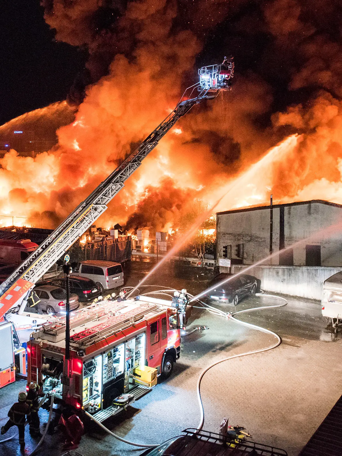 26.09.2021, Hamburg: Feuerwehrleute löschen im Stadtteil Rothenburgsort einen Großbrand. Auf einem Industriegelände sind in der Nacht vermutlich Sperrmüll und Elektrogeräte in Brand geraten, anschließend griff das Feuer auf eine Lagerhalle über. (zu dpa «Brand einer Lagerhalle in Hamburg - große Rauchsäule am Himmel») Foto: Daniel Bockwoldt/dpa +++ dpa-Bildfunk +++