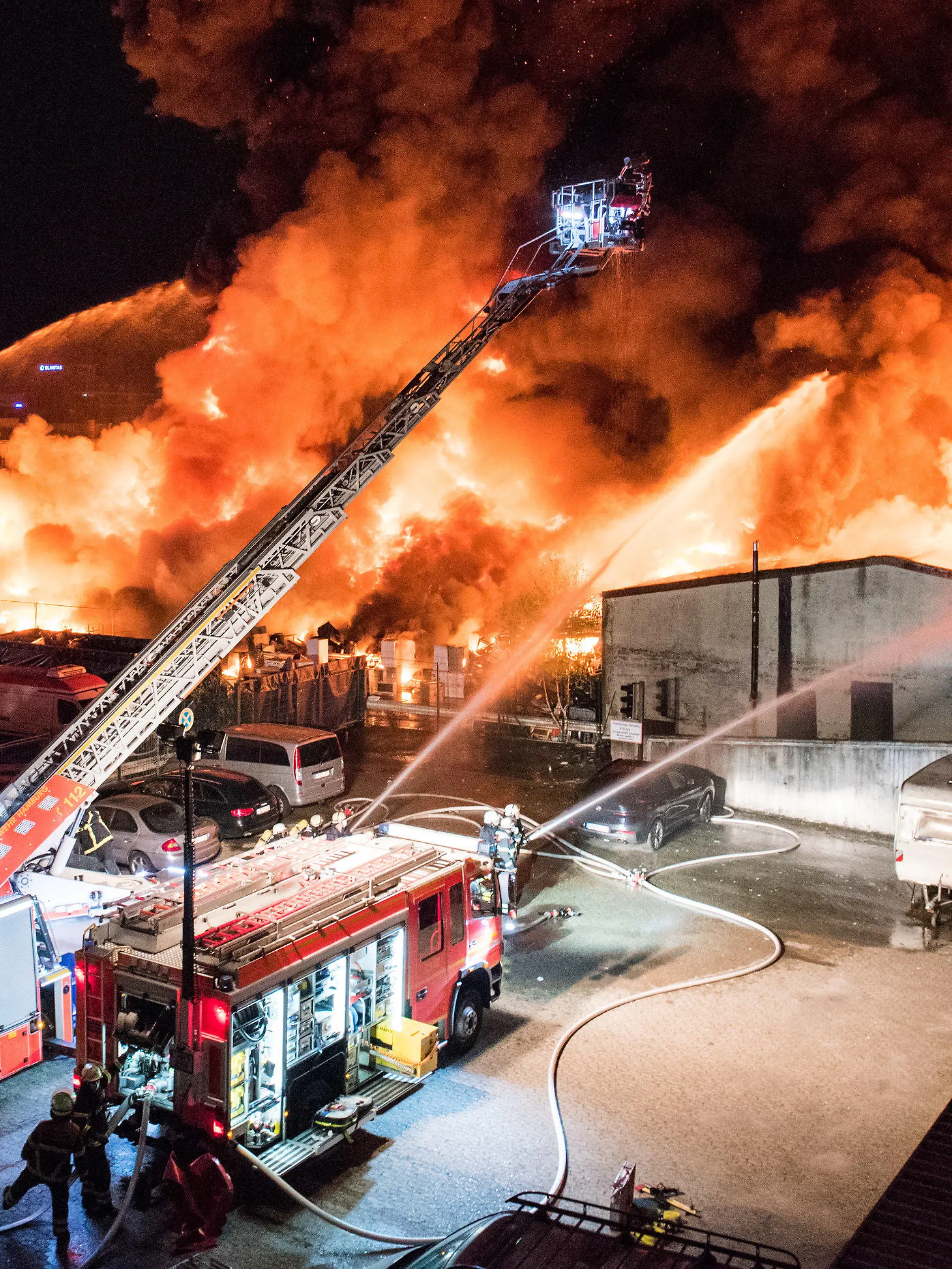 26.09.2021, Hamburg: Feuerwehrleute löschen im Stadtteil Rothenburgsort einen Großbrand. Auf einem Industriegelände sind in der Nacht vermutlich Sperrmüll und Elektrogeräte in Brand geraten, anschließend griff das Feuer auf eine Lagerhalle über. (zu dpa «Brand einer Lagerhalle in Hamburg - große Rauchsäule am Himmel») Foto: Daniel Bockwoldt/dpa +++ dpa-Bildfunk +++