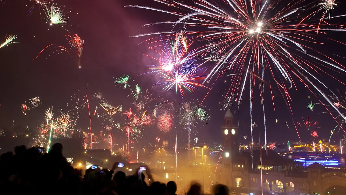 ARCHIV - 31.12.2013, Hamburg: Tausende Menschen begrüßen an den Landungsbrücken mit einem Feuerwerk das neue Jahr. An Silvester und Neujahr wird in Deutschland angesichts der sich ausbreitenden Corona-Pandemie ein bundesweites An- und Versammlungsverbot gelten. Foto: Angelika Warmuth/dpa +++ dpa-Bildfunk +++