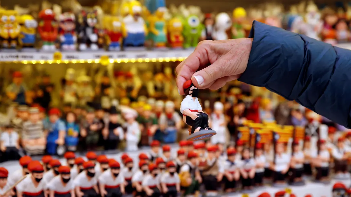 A woman holds a clay "caganer" figure wearing a mask, which symbolises defecation and fertilisation of the earth, and is believed to bring prosperity and luck for the coming year, at the Santa Llucia Christmas market in central Barcelona, during the coronavirus disease (COVID-19) outbreak, in Barcelona, Spain, December 17, 2020.  REUTERS/Albert Gea