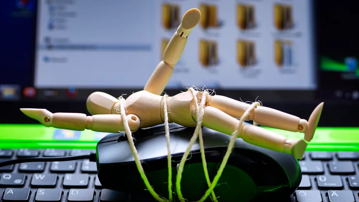 Holzpuppe auf Computermouse gefesselt und Computer, Symbolfoto kinderpornografische Fotos im Internet