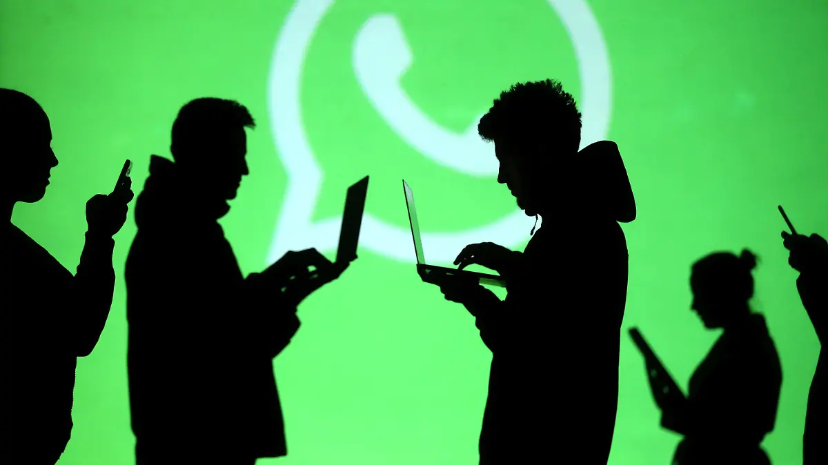 REFILE - CLARIFYING CAPTION Silhouettes of laptop and mobile device users are seen next to a screen projection of Whatsapp logo in this picture illustration taken March 28, 2018. REUTERS/Dado Ruvic/Illustration