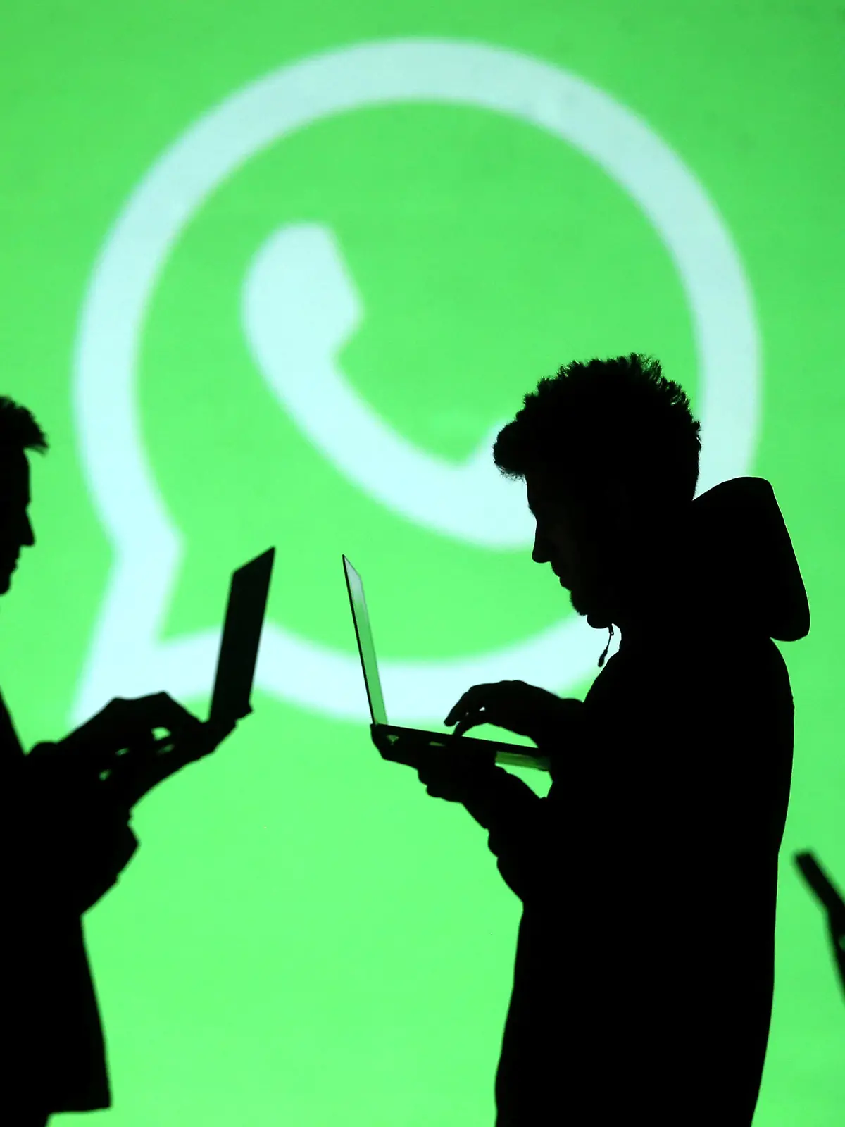 REFILE - CLARIFYING CAPTION Silhouettes of laptop and mobile device users are seen next to a screen projection of Whatsapp logo in this picture illustration taken March 28, 2018.  REUTERS/Dado Ruvic/Illustration