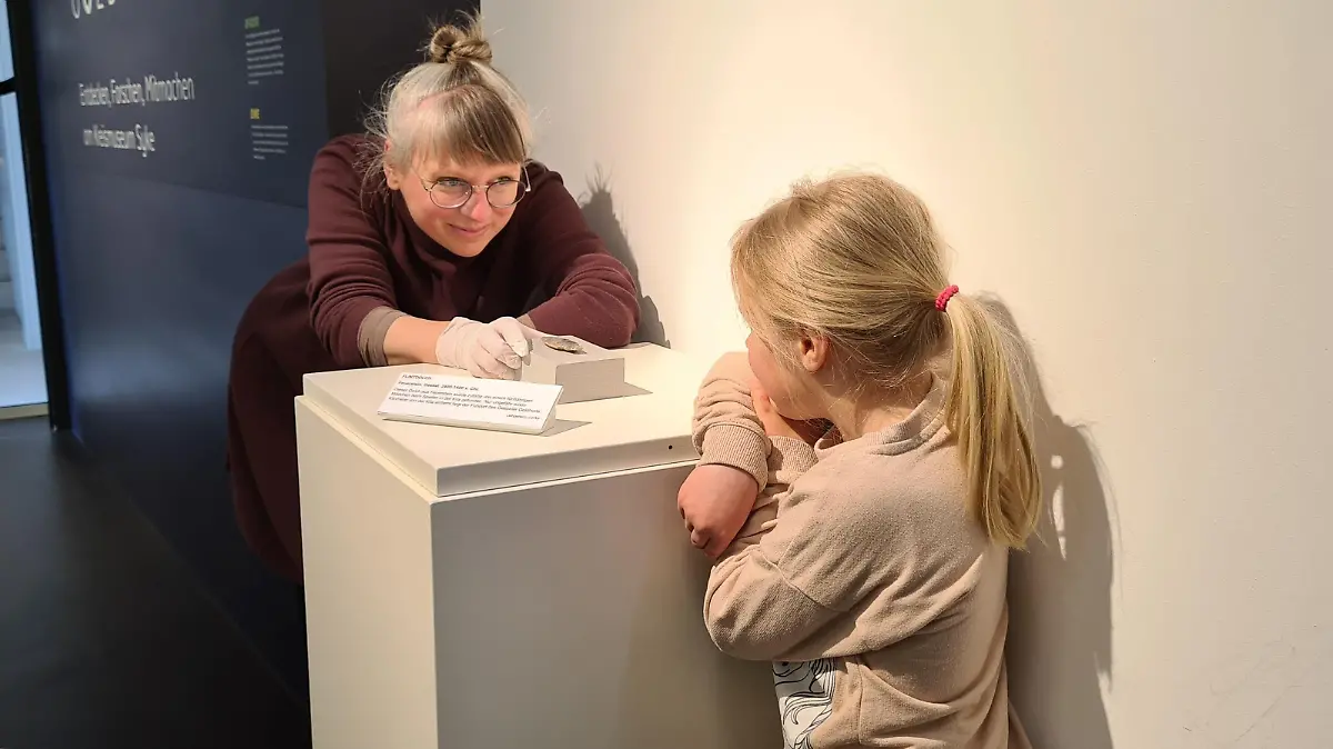 Finderin Levke (5) bewundert ihren Schatz mit Kuratorin Nele Miethia vom Kreismuseum Syke und Forum Gesseler Goldhort.