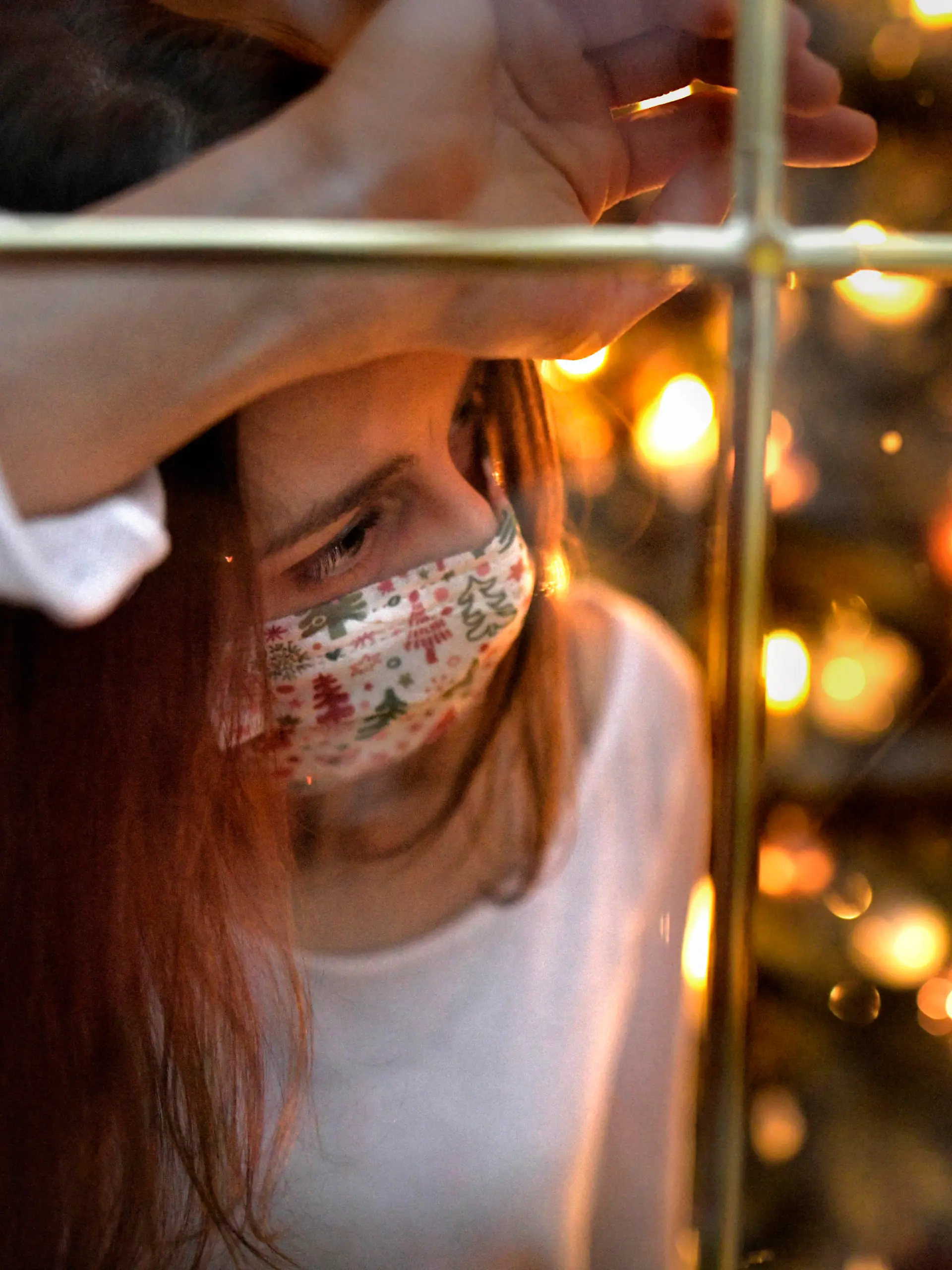21.11.2020, Modelreleased. Symbolbild, Eine Frau mit Mund-Nasenschutz-Maske schaut sehnsüchtig aus dem Wohnzimmerfenster, innen brennen die kerzen des Weihnachstbaumes, sie ist alleine. Angst vor Einsamkeit wegen Corona am Heiligen Abend. Kontaktverbote und Ausgangsbeschränkungen machen der Bevölkerung das Leben schwer, die gewohnten Treffen unter den Familien könnte es dieses Jahr wegen der Pandemiebeschränkungen nicht geben. Depressionen können die Folge sein. 21.11.2020, Weihnachten in Einsamkeit wegen Corona 21.11.2020, Weihnachten in Einsamkeit wegen Corona *** 21 11 2020, Modelreleased symbol image, A woman with mouth Nose protection Mask looks longingly out of the living room window, inside the candles of the Christmas tree 