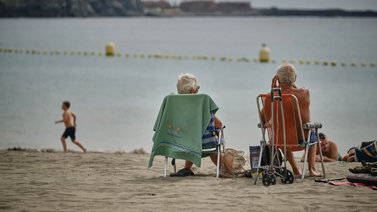 25.10.2020, Spanien, Los Cristianos: Touristen genießen die Sonne am Strand La Playa de Las Vistas im Süden der Kanaren-Insel. Deutsche und britische Touristen trafen an diesem Wochenende auf der Kanareninsel ein, nachdem die Kanaren wegen sinkender Infektionszahlen wieder von der Risikoliste gestrichen worden sind. Zur Eindämmung der rapide steigenden Corona- Infektionszahlen hat die Regierung in Spanien erneut den nationalen Notstand ausgerufen. Die Anordnung gilt praktisch für das ganze Land - ausgenommen sind nur die Kanaren. Foto: Andrés Gutiérrez/dpa +++ dpa-Bildfunk +++