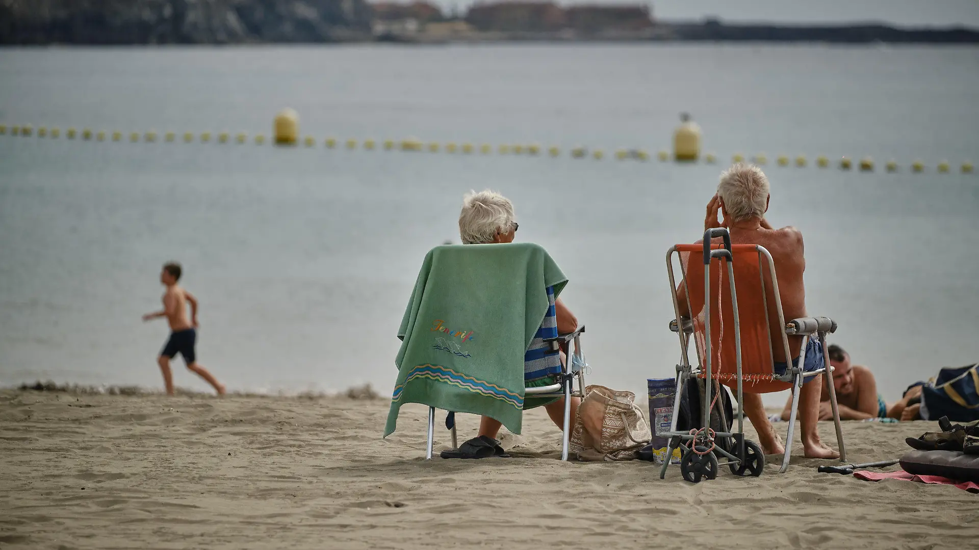 25.10.2020, Spanien, Los Cristianos: Touristen genießen die Sonne am Strand La Playa de Las Vistas im Süden der Kanaren-Insel. Deutsche und britische Touristen trafen an diesem Wochenende auf der Kanareninsel ein, nachdem die Kanaren wegen sinkender Infektionszahlen wieder von der Risikoliste gestrichen worden sind. Zur Eindämmung der rapide steigenden Corona- Infektionszahlen hat die Regierung in Spanien erneut den nationalen Notstand ausgerufen. Die Anordnung gilt praktisch für das ganze Land - ausgenommen sind nur die Kanaren. Foto: Andrés Gutiérrez/dpa +++ dpa-Bildfunk +++