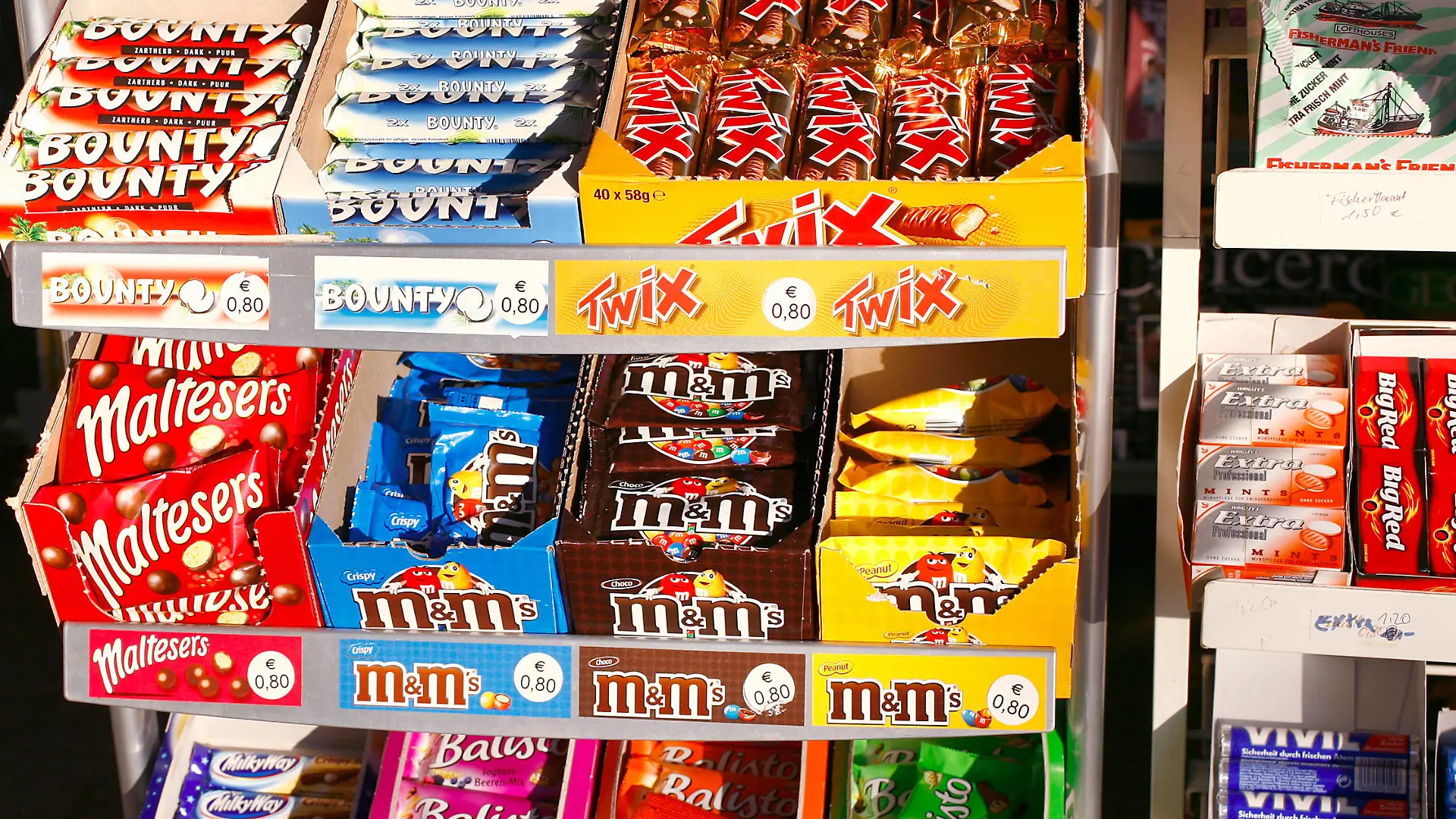Süßigkeiten und Schokoriegel liegen in einem Regal eines Kioskes in Frankfurt am Main im Dezember 2007. Solches süßes Fast Food ist ungesund, teuer und macht dick. Den meist internationalen Herstellern bescheren die Schokoriegel aber weltweit hohe Gewinne. Foto: Wolfram Steinberg +++(c) dpa - Report+++