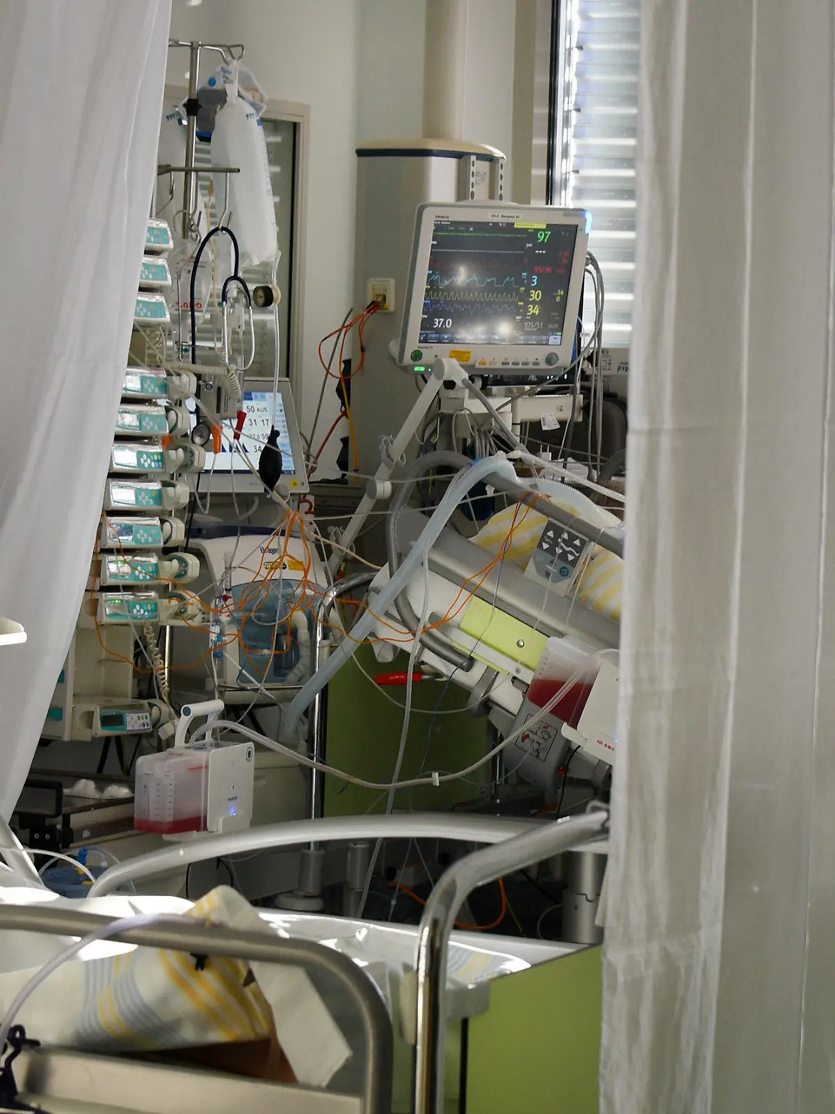 24.11.2020, Sachsen, Leipzig: Auf der Covid-19-Station, einem Bereich der Operativen Intensivstation vom Universitätsklinikum Leipzig, versorgt eine Intensivkrankenschwester schwerkranke Patienten. Auf der Intensivstation wächst seit Tagen die Zahl der Corona-Erkrankten mit schweren Verläufen, darunter immer mehr jüngere Patenten zwischen 30 und 60 Jahren. Foto: Waltraud Grubitzsch/dpa-Zentralbild/dpa +++ dpa-Bildfunk +++