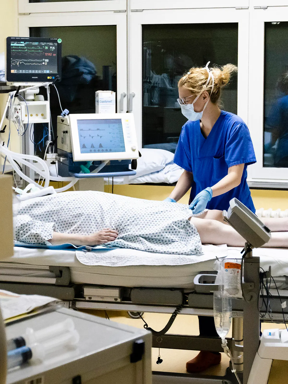 03.12.2020, Schleswig-Holstein, Kiel: Melina Lütje, Krankenschwester auf der Intensivstation am Universitätsklinikum Schleswig-Holstein, steht am Bett einer Patientin. Die Zahl der Corona-Patienten auf deutschen Intensivstationen hat erstmals die Schwelle von 4000 überschritten. Am Freitag meldete die Deutsche Interdisziplinären Vereinigung für Intensiv- und Notfallmedizin (Divi) 4011 Menschen in intensivmedizinischer Behandlung. Das waren 31 mehr als am Vortag, wie aus dem DIVI-Tagesbericht hervorgeht. 60 Prozent der Patienten werden invasiv beatmet (Stand: 04.12., 12.15 Uhr). Foto: Frank Molter/dpa +++ dpa-Bildfunk +++