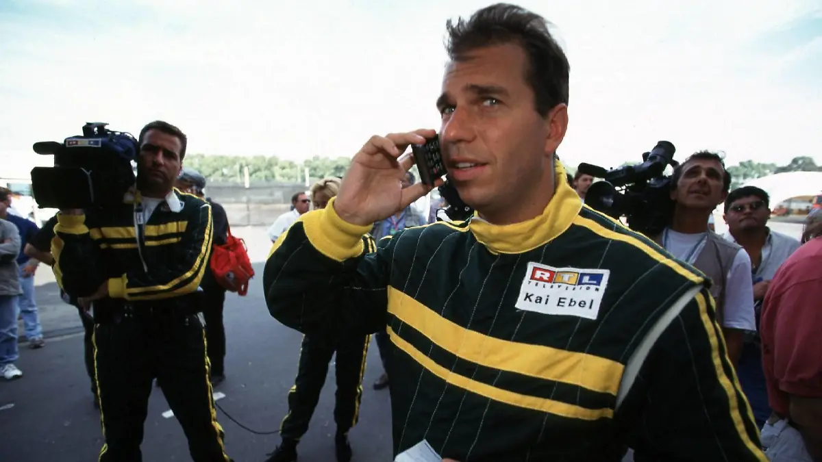 RTL-Moderator Kai Ebel mit Handy telefonierend in der Boxengasse