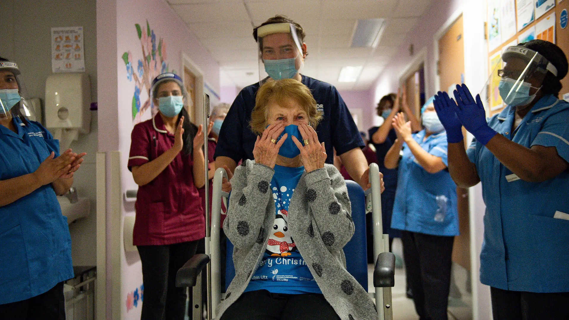Margaret Keenan, 90, is applauded by staff as she returns to her ward after becoming the first patient in the UK to receive the Pfizer-BioNTech COVID-19 vaccine, at University Hospital, Coventry, England, Tuesday Dec. 8, 2020. The United Kingdom, one of the countries hardest hit by the coronavirus, is beginning its vaccination campaign, a key step toward eventually ending the pandemic. (Jacob King/Pool via AP)