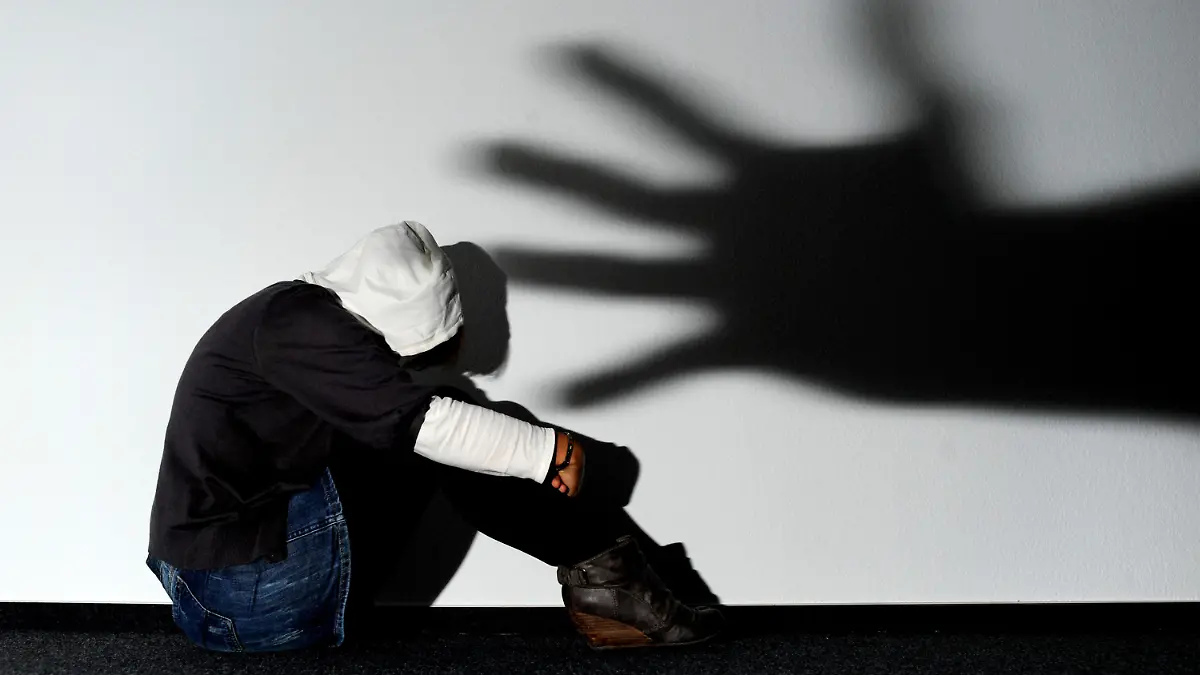 ARCHIV - ILLUSTRATION - Ein Mädchen sitzt am 14.09.2011 vor einer Wand in Hannover, auf der der Schatten einer Hand groß zu sehen ist (Symbolbild zum Thema Opfer von Gewalttaten). Opfer schwerer Straftaten in Mecklenburg-Vorpommern sollen eine bessere Unterstützung erhalten. Landesweit wird das Angebot der psychosozialen Prozessbegleitung auf den Weg gebracht. (zu dpa «Landtag will Gesetz für psychosoziale Prozessbegleitung beschließen» vom 17.05.2017) Foto: Julian Stratenschulte/dpa +++(c) dpa - Bildfunk+++