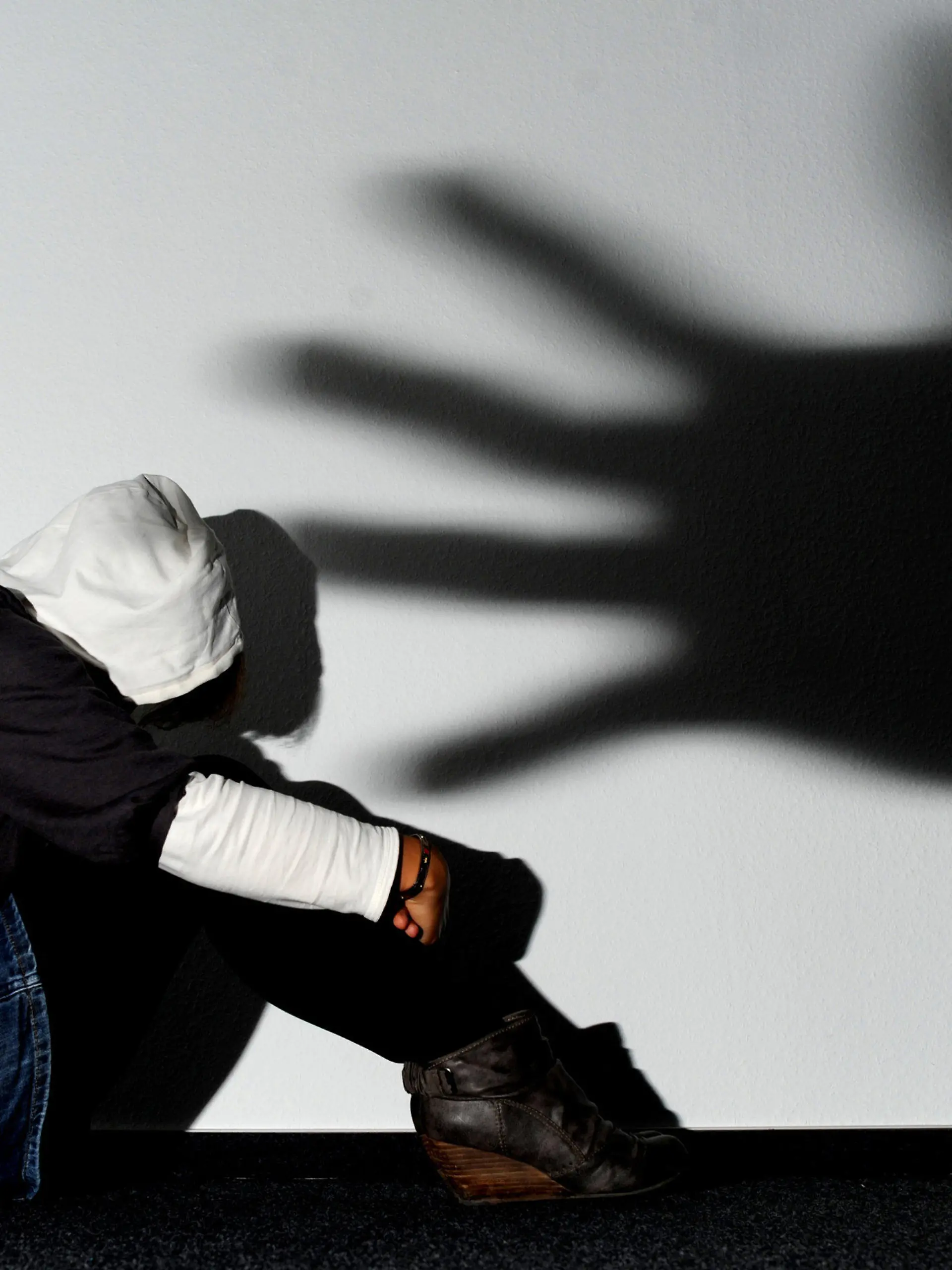 ARCHIV - ILLUSTRATION - Ein Mädchen sitzt am 14.09.2011 vor einer Wand in Hannover, auf der der Schatten einer Hand groß zu sehen ist (Symbolbild zum Thema Opfer von Gewalttaten). Opfer schwerer Straftaten in Mecklenburg-Vorpommern sollen eine bessere Unterstützung erhalten. Landesweit wird das Angebot der psychosozialen Prozessbegleitung auf den Weg gebracht. (zu dpa «Landtag will Gesetz für psychosoziale Prozessbegleitung beschließen» vom 17.05.2017) Foto: Julian Stratenschulte/dpa +++(c) dpa - Bildfunk+++