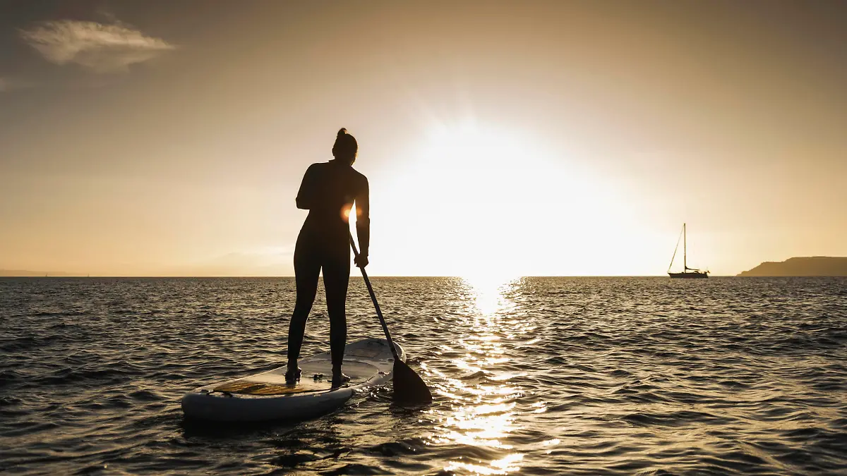 Young woman stand up paddle surfing at sunset || Modellfreigabe vorhanden