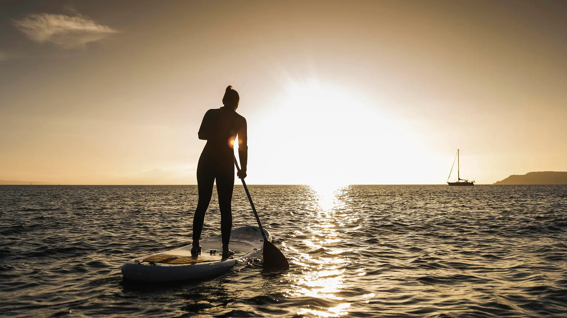 Young woman stand up paddle surfing at sunset || Modellfreigabe vorhanden