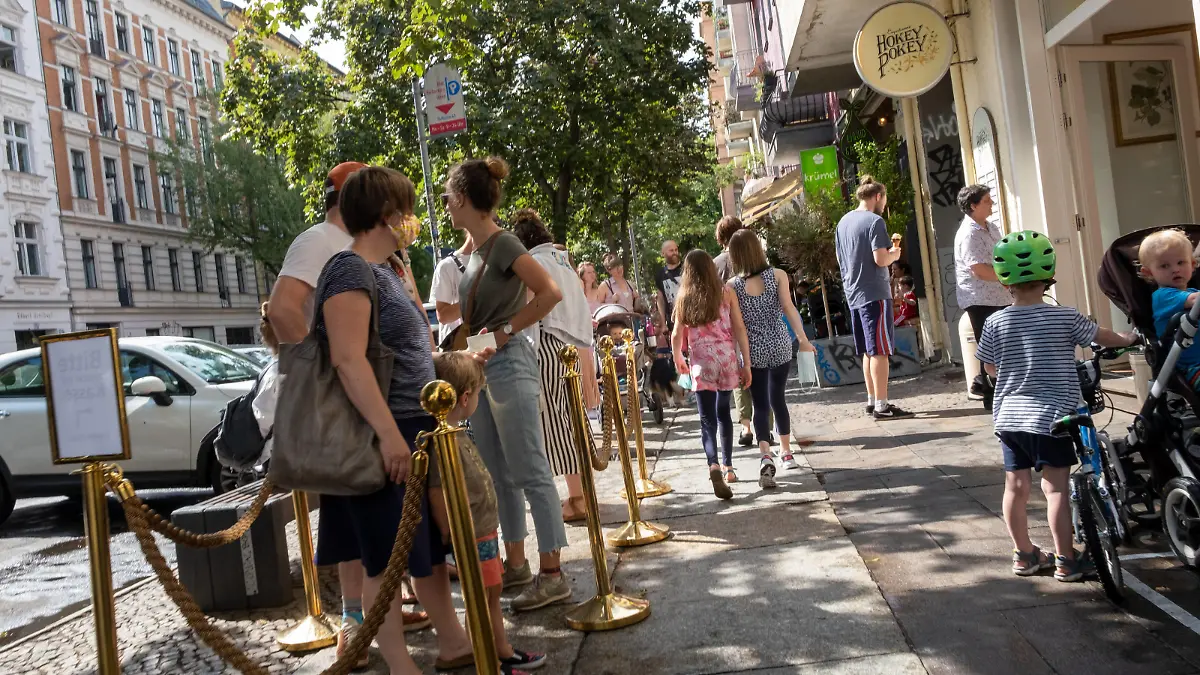 Menschen mit Corona-Masken stehen vor Berliner Eisdiele in der Warteschlange