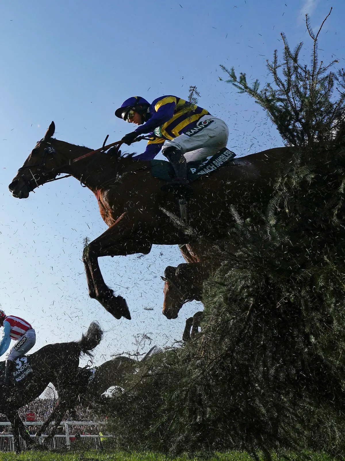 Derek Fox on Corach Rambler, top, clears the Chair fence on the way to winning the Grand National horse race at Aintree Racecourse Liverpool, England, Saturday, April 15, 2023. The iconic Grand National race which is run over fences is 4 miles, 2 ½ furlongs has its origins in the 1839 Grand Liverpool Steeplechase. (AP Photo/Jon Super)