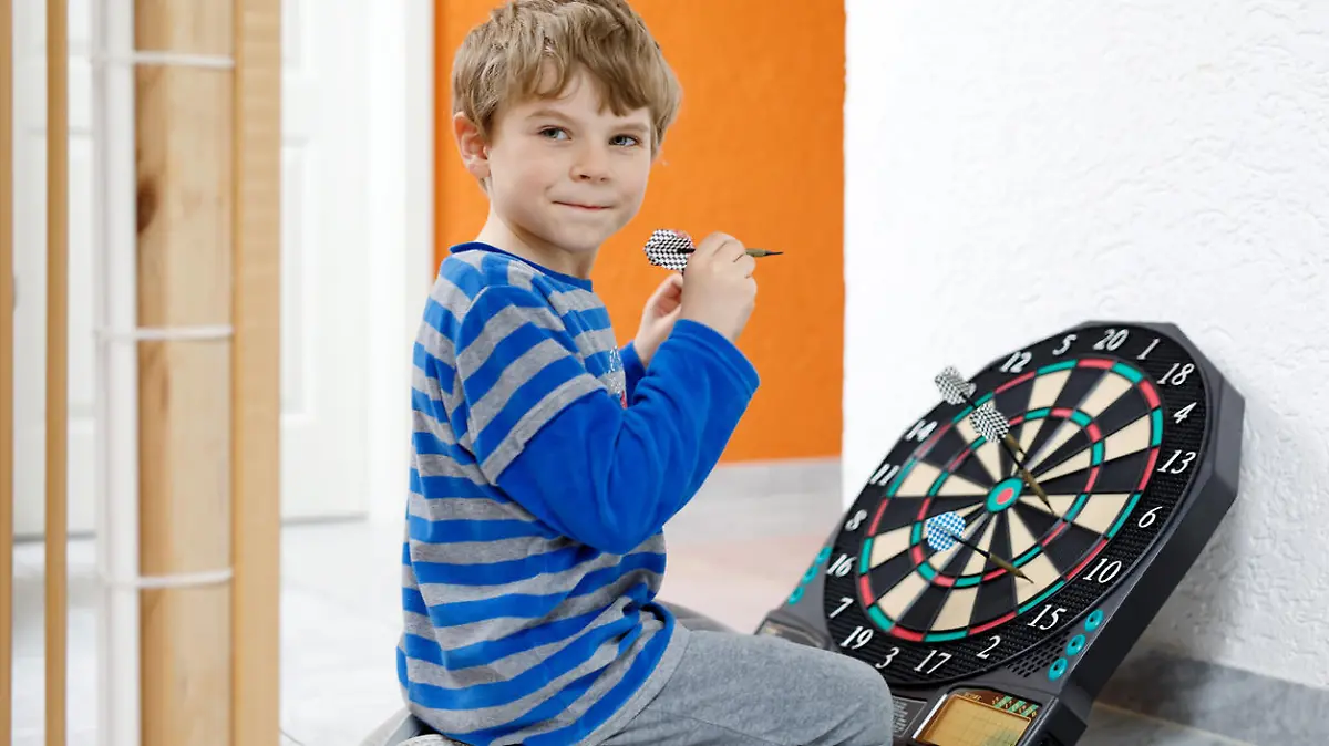 Kind spielt mit einer Dartscheibe.