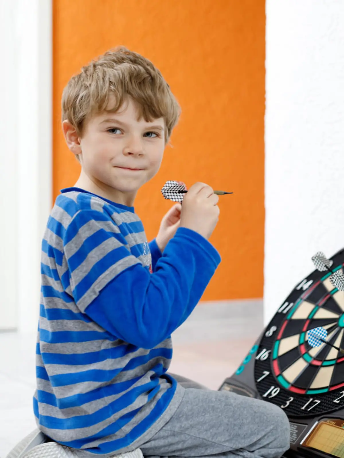 Kind spielt mit einer Dartscheibe.