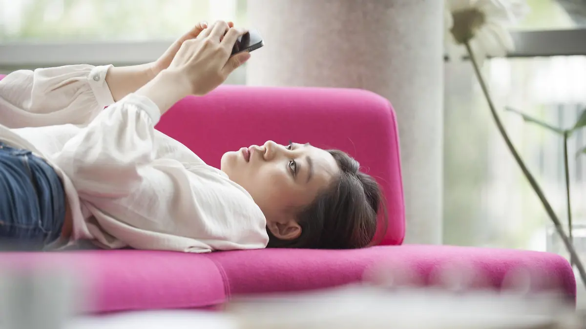 Woman relaxing at home using smartphone PUBLICATIONxINxGERxSUIxAUTxONLY Copyright: OdilonxDimier B27279227