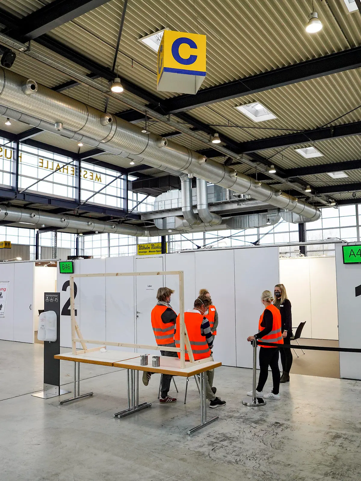 03.12.2020, Schleswig-Holstein, Husum: Mitarbeiter der Messe Husum simulieren bei der Vorstellung der Impfstraße in einem künftigen Corona-Impfzentrum in den Messehallen einen Impfvorgang. Bei einem Testlauf soll geprüft werden, ob der Arbeitsablauf vom Eintreffen der Menschen, die geimpft werden sollen, bis zu ihrer Abfahrt klappt wie geplant oder ob noch Änderungsbedarf besteht. Foto: Axel Heimken/dpa +++ dpa-Bildfunk +++