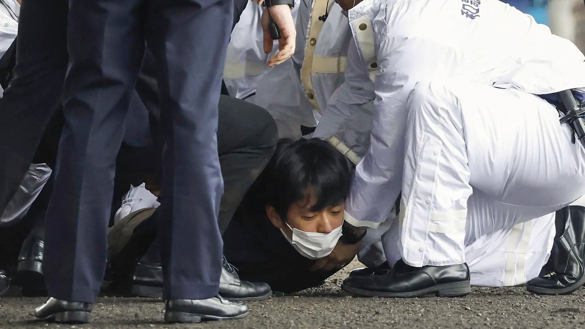 15.04.2023, Japan, Wakayama: Ein Mann wird am Boden festgehalten, nachdem in einem Hafen in Wakayama im Westen Japans eine Rauchbombe geworfen wurde. Während eines Wahlkampfauftritts des japanischen Regierungschefs Fumio Kishda ist in der Nähe eine Rauchbombe explodiert. Kishida sei unverletzt in Sicherheit gebracht worden, berichtete der japanische Fernsehsender NHK am Samstag aus der Präfektur Wakayama. Foto: Uncredited/Kyodo News/AP/dpa +++ dpa-Bildfunk +++