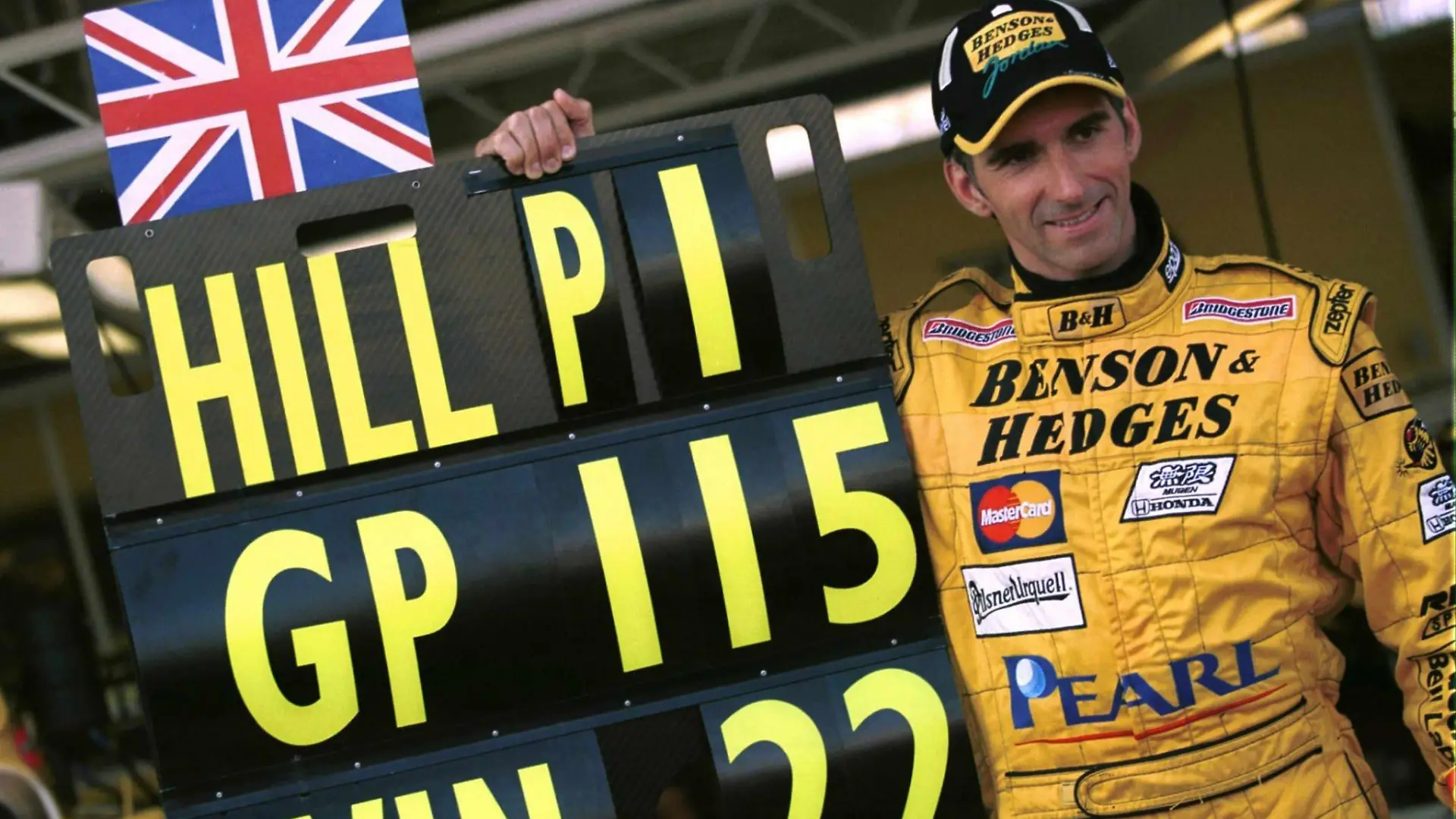 Der britische Formel 1-Pilot Damon Hill von Jordan-Mugen-Honda posiert am 31.10.1999 mit einer Tafel, die seine 22 Grand-Prix-Siege in 115 Rennen wiedergibt. Der frühere Weltmeister startet am 31.10.1999 beim Großen Preis von Japan in Suzuka zu seinem letzten Rennen. Der 39-jährige Hill beendet damit nach acht Jahren seine Karriere.