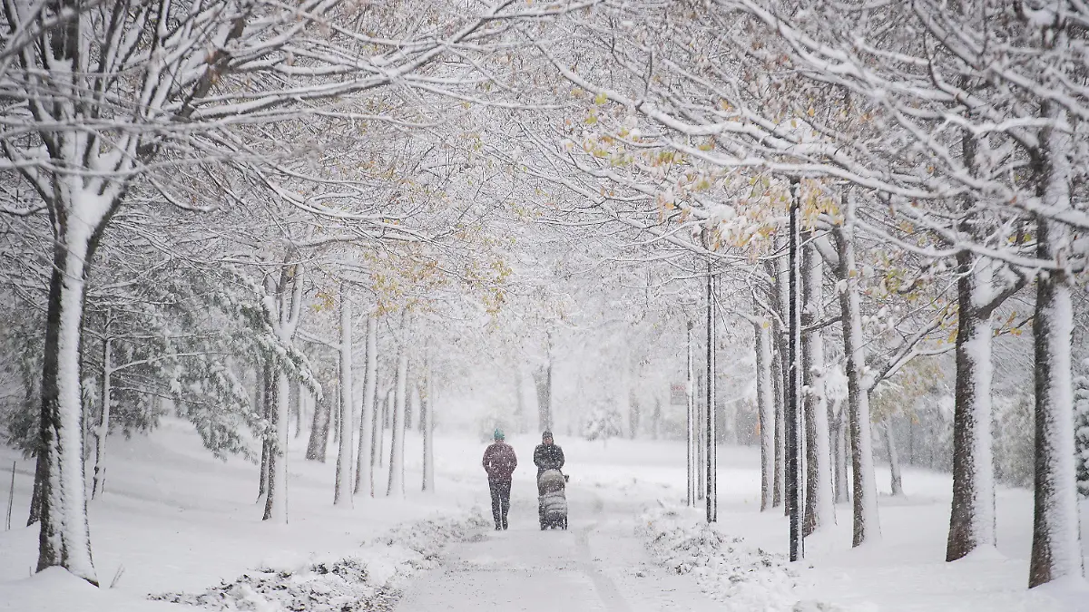 16.11.2022, Kanada, Montreal: Menschen gehen nach dem ersten Schneefall mit einem Kinderwagen durch einen schneebedeckten Park spazieren. Foto: Graham Hughes/Canadian Press via ZUMA Press/dpa +++ dpa-Bildfunk +++