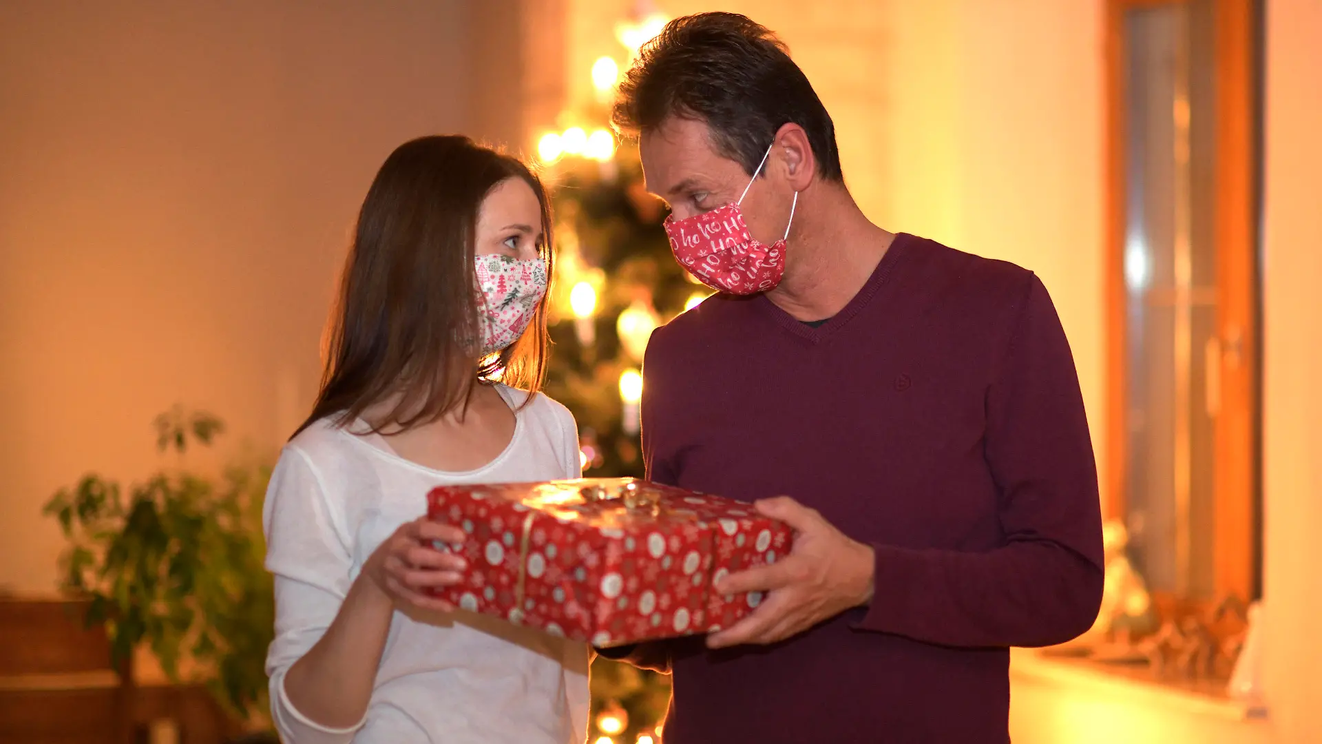 24.11.2020, Modelreleased. Symbolbild, Ehepaar beschenkt sich an Heilig Abend, beide haben Mund-Nasen-Masken auf. Kontaktverbote und Ausgangsbeschränkungen machen der Bevölkerung zur Corona-Zeit das Leben schwer, die gewohnten Treffen unter den Familien sind dieses Jahr wegen der Pandemiebeschränkungen nur Eingeschränkt möglich. 24.11.2020, Paar feiert Weihnachten mit Corona-Einschränkungen 24.11.2020, Paar feiert Weihnachten mit Corona-Einschränkungen *** 24 11 2020, Modelreleased symbolic picture, married couple gives each other presents on Christmas Eve, both have mouth-noses Masks on contact restrictions and exit restrictions make life difficult for the population during Corona time, the usual family gatherings are limited