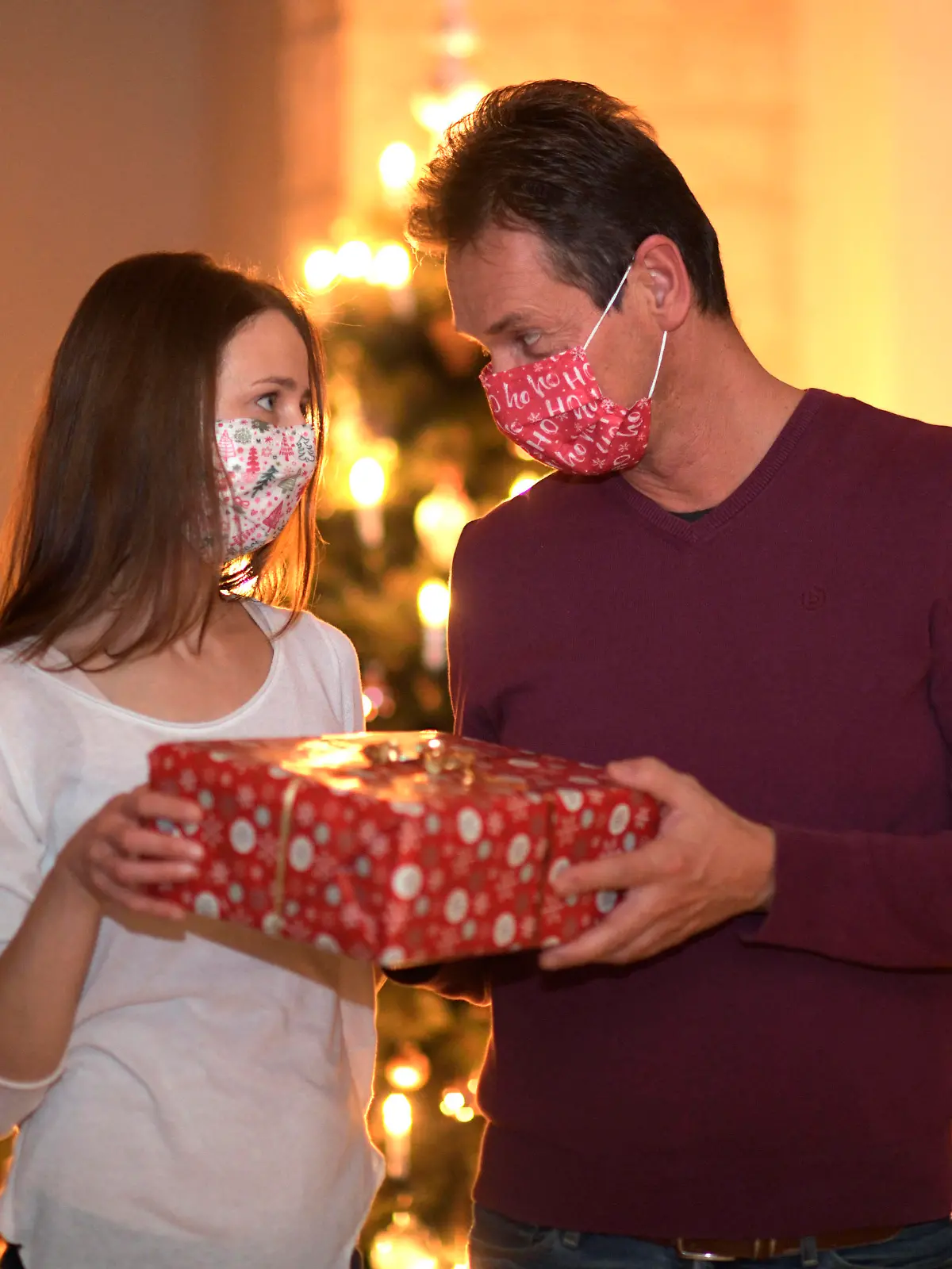 24.11.2020, Modelreleased. Symbolbild, Ehepaar beschenkt sich an Heilig Abend, beide haben Mund-Nasen-Masken auf. Kontaktverbote und Ausgangsbeschränkungen machen der Bevölkerung zur Corona-Zeit das Leben schwer, die gewohnten Treffen unter den Familien sind dieses Jahr wegen der Pandemiebeschränkungen nur Eingeschränkt möglich. 24.11.2020, Paar feiert Weihnachten mit Corona-Einschränkungen 24.11.2020, Paar feiert Weihnachten mit Corona-Einschränkungen *** 24 11 2020, Modelreleased symbolic picture, married couple gives each other presents on Christmas Eve, both have mouth-noses Masks on contact restrictions and exit restrictions make life difficult for the population during Corona time, the usual family gatherings are limited 