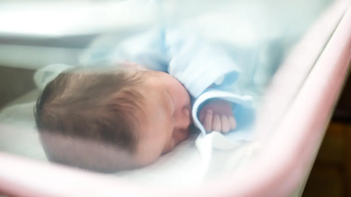 Neugeborenes Baby schläft im Krankenhausbett.