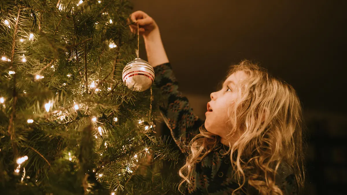 Mädchen schmückt Weihnachtsbaum