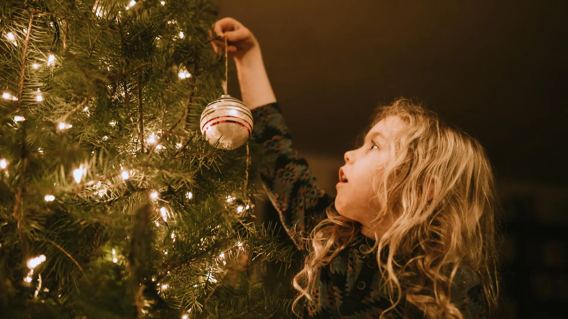 Mädchen schmückt Weihnachtsbaum
