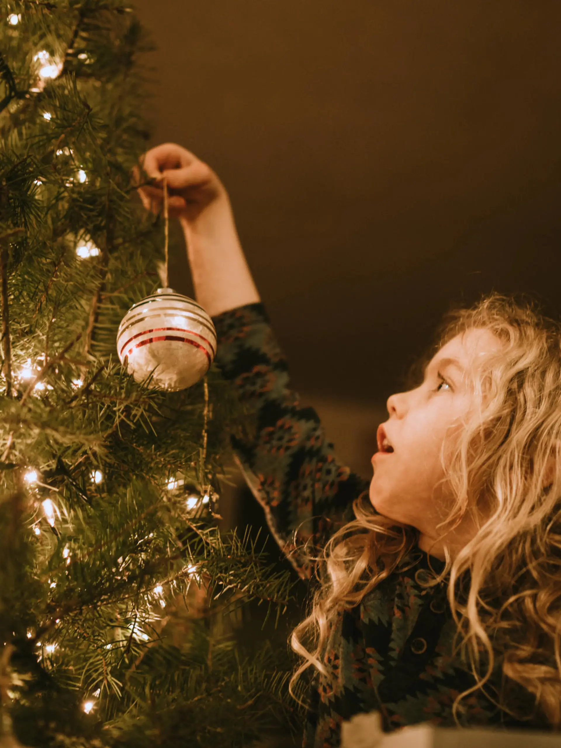 Mädchen schmückt Weihnachtsbaum