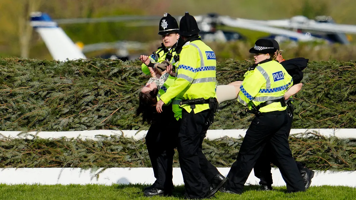 Members of the police forces remove a protester before the start of the Grand National horse race at Aintree Racecourse Liverpool, England, Saturday, April 15, 2023. The iconic Grand National race which is run over fences is 4 miles, 2 ½ furlongs has its origins in the 1839 Grand Liverpool Steeplechase.(AP Photo/Jon Super)