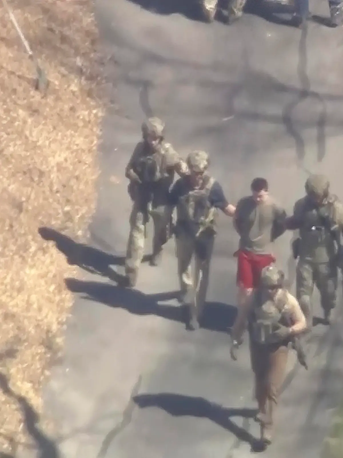 This image made from video provided by WCVB-TV, shows Jack Teixeira, in T-shirt and shorts, being taken into custody by armed tactical agents on Thursday, April 13, 2023, in Dighton, Mass. (WCVB-TV via AP)