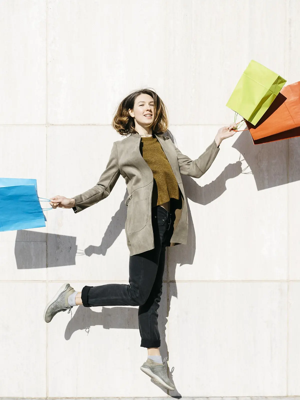  Cheerful woman with shopping bags jumping at a wall model released Symbolfoto PUBLICATIONxINxGERxSUIxAUTxHUNxONLY JRFF02783