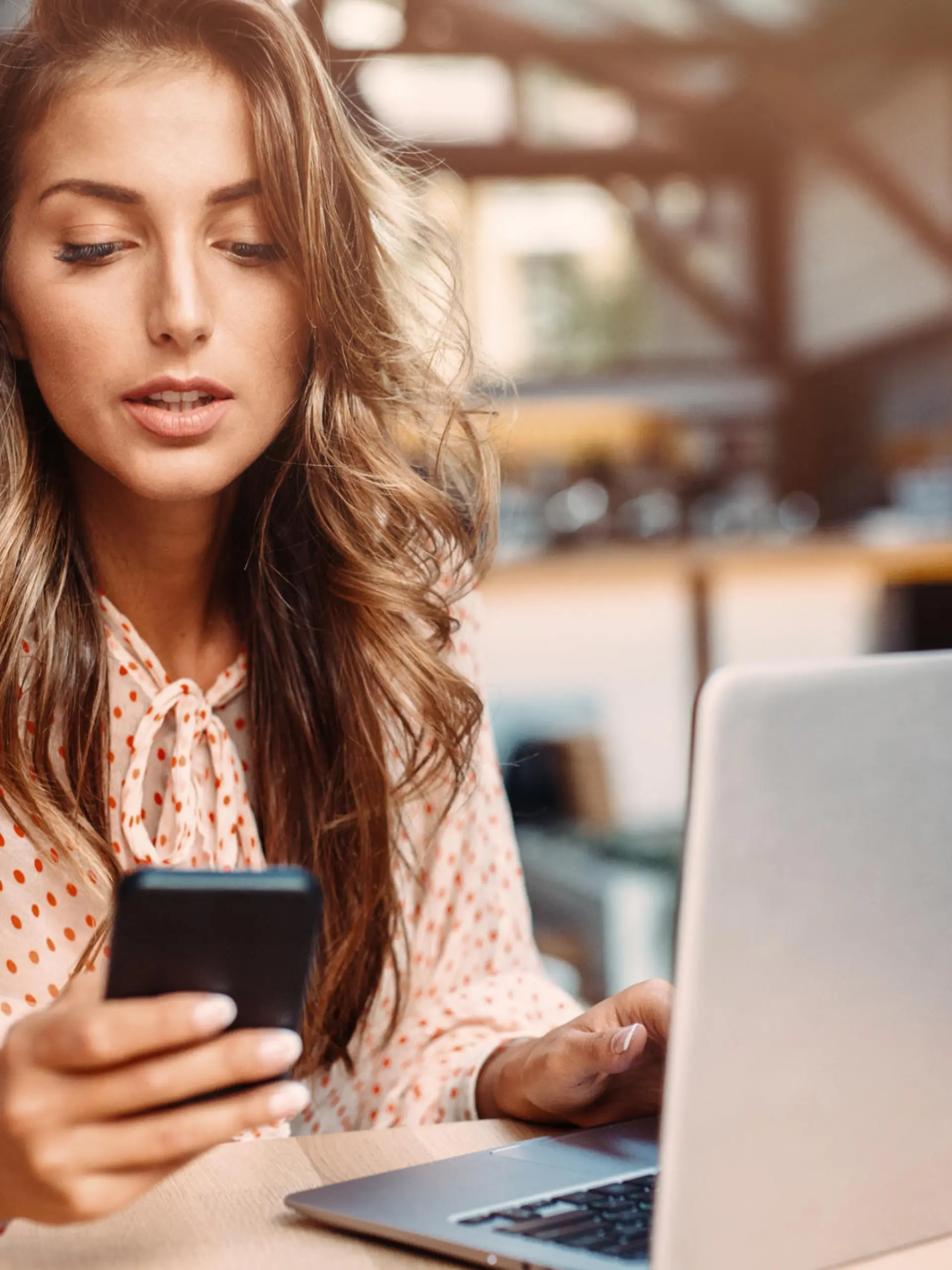 Young lady  texting while using a laptop at the cafe.