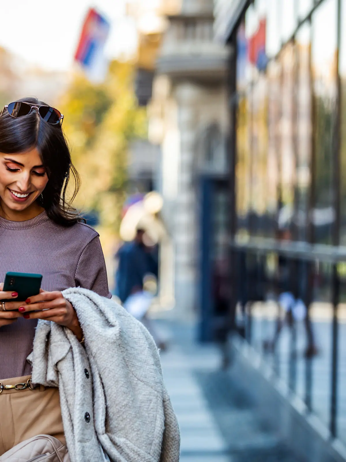 Shot of a beautiful mature businesswoman texting. Mature businesswoman walking outdoors and using cellphone. Female business professional walking outside and texting from her mobile phone.