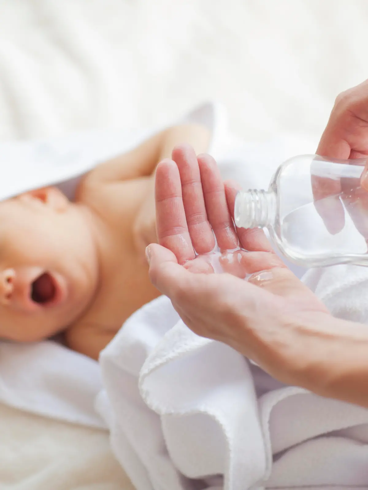 Ölflasche im Fokus, Säugling nach Bad im Hintergrund