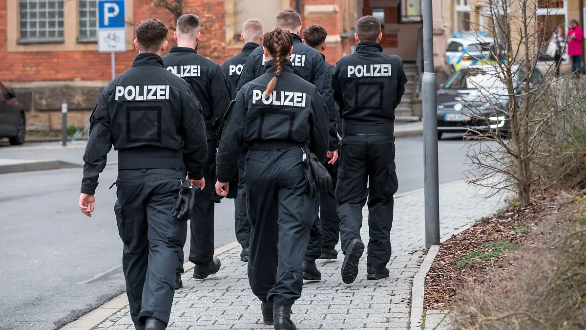 13.03.2023, Bayern, Lichtenfels: Mehrere Einsatzkräfte der Polizei gehen das Gebiet um das Blumengeschäft ab, in dem am Freitagabend eine leblose Frau aufgefunden wurde. Foto: Daniel Vogl/dpa +++ dpa-Bildfunk +++