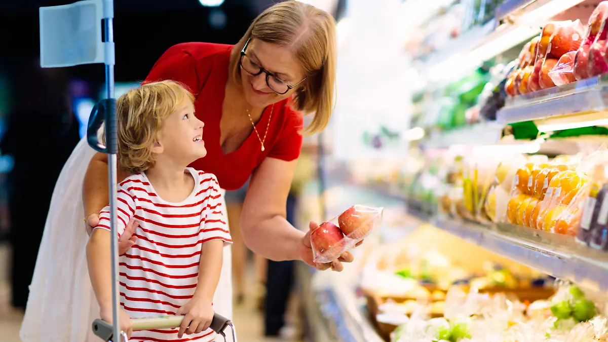 Shopping with kids. Mother and child buying fruit in supermarket. Mom and little boy buy fresh mango in grocery store. Family in shop. Parent and children in a mall choosing vegetables. Healthy food.