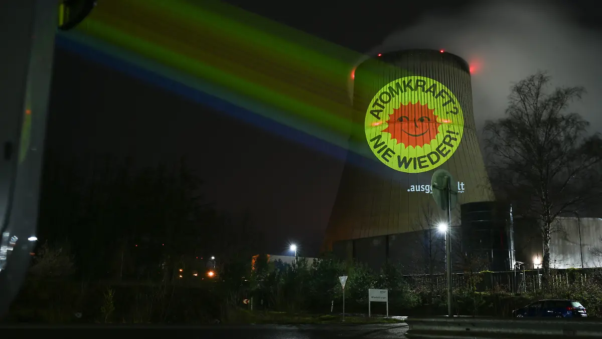 10.04.2023, Niedersachsen, Lingen: Aktivisten der Anti-Atom-Bewegung projizieren eine große Anti-Atom-Sonne auf den Kühlturm des Atomkraftwerkes Emsland. Anlass ist die Abschaltung der letzten AKW am 15. April. Die ursprünglich aus Dänemark stammende rote Anti-Atom-Sonne auf gelbem Grund ist zum weltweiten Symbol dieser Bewegung geworden. Foto: Lars Klemmer/dpa +++ dpa-Bildfunk +++
