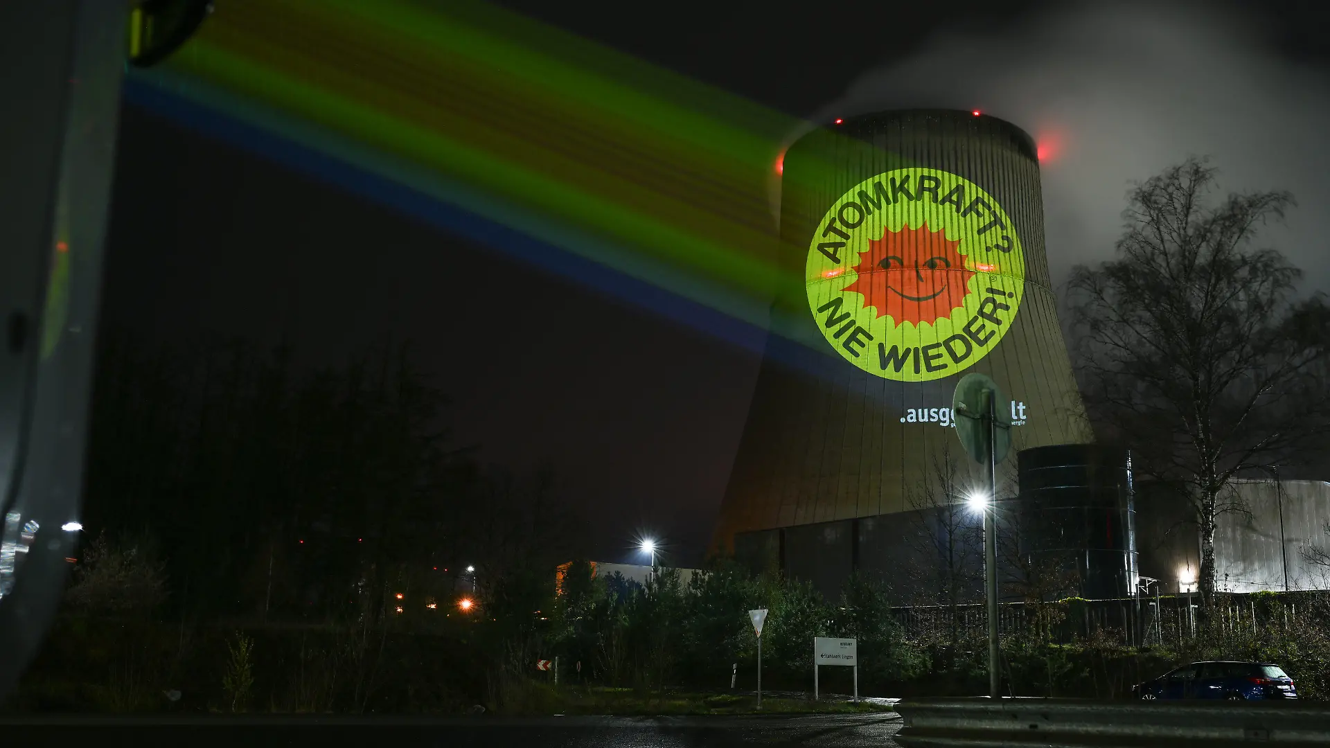 10.04.2023, Niedersachsen, Lingen: Aktivisten der Anti-Atom-Bewegung projizieren eine große Anti-Atom-Sonne auf den Kühlturm des Atomkraftwerkes Emsland. Anlass ist die Abschaltung der letzten AKW am 15. April. Die ursprünglich aus Dänemark stammende rote Anti-Atom-Sonne auf gelbem Grund ist zum weltweiten Symbol dieser Bewegung geworden. Foto: Lars Klemmer/dpa +++ dpa-Bildfunk +++