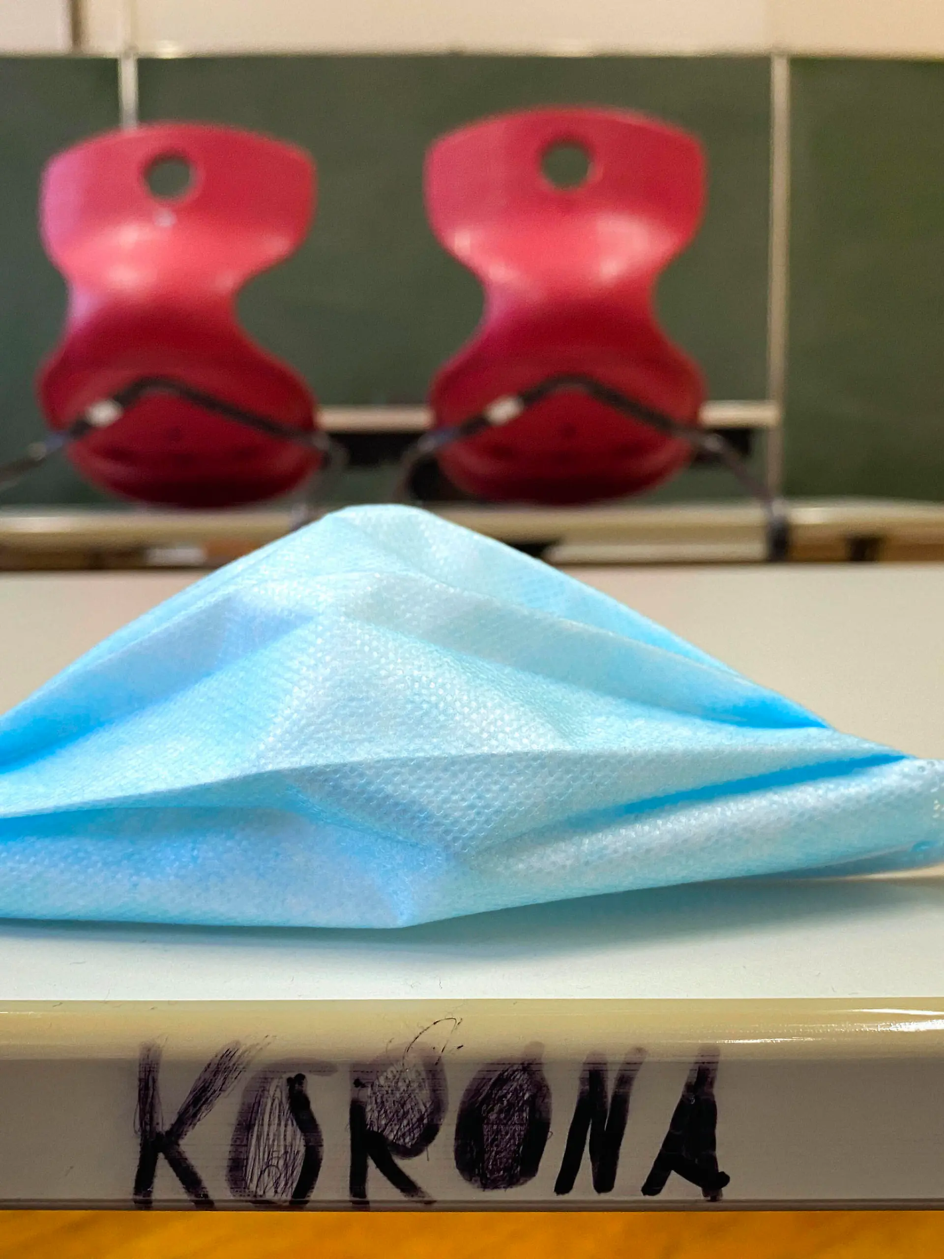  leeres Klassenzimmer, aufgestuhlt, Mundschutzmaske und Schriftzug KORONA auf Tisch, Einzeltische ohne Abstandsregel, Corona-Krise, Deutschland Leeres Klassenzimmer Corona-Krise *** Empty classroom, seated, face mask and lettering KORONA on table, single tables without distance rule, Corona crisis, Germany Empty classroom Corona crisis