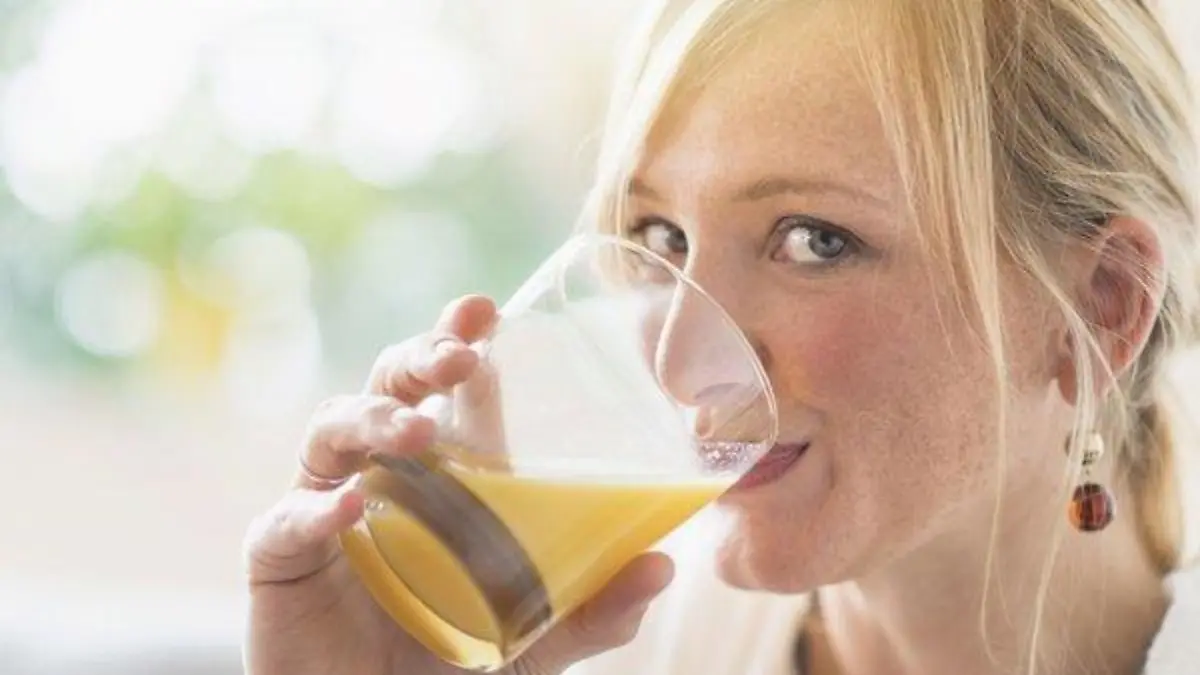 Woman sitting in living room and drinking orange juice, Frau, die im Wohnzimmer sitzt und Orangensaft trinkt Keine Weitergabe an Drittverwerter.