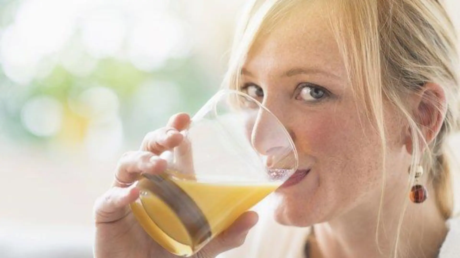 Woman sitting in living room and drinking orange juice, Frau, die im Wohnzimmer sitzt und Orangensaft trinkt Keine Weitergabe an Drittverwerter.