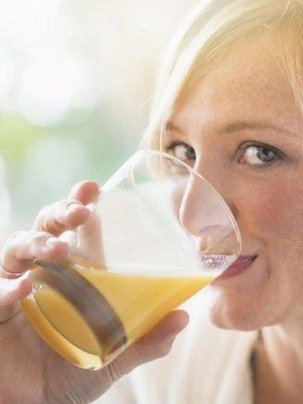 Woman sitting in living room and drinking orange juice, Frau, die im Wohnzimmer sitzt und Orangensaft trinkt Keine Weitergabe an Drittverwerter.